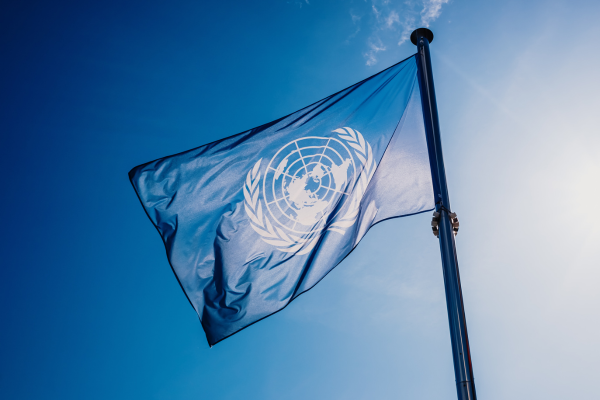 A United Nations flag against a bright blue sky