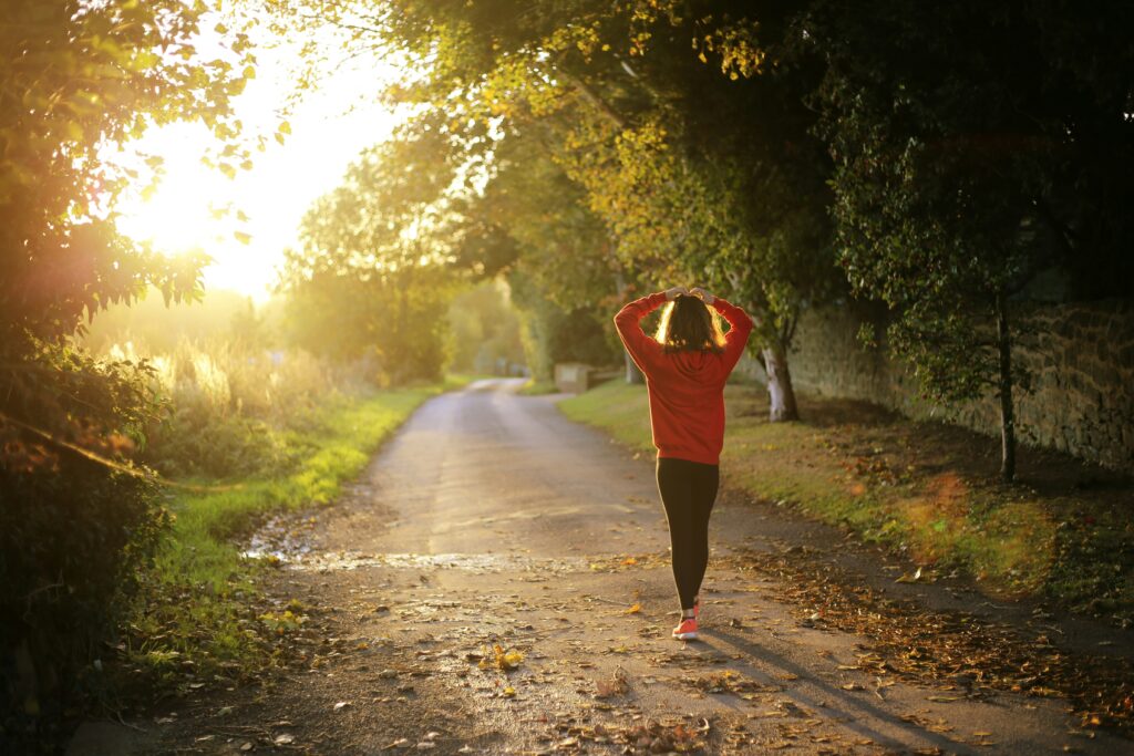 Woman walking in the forest in the sunsat